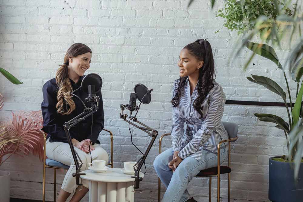 2 orang podcaster wanita sedang mengobrol dengan mic