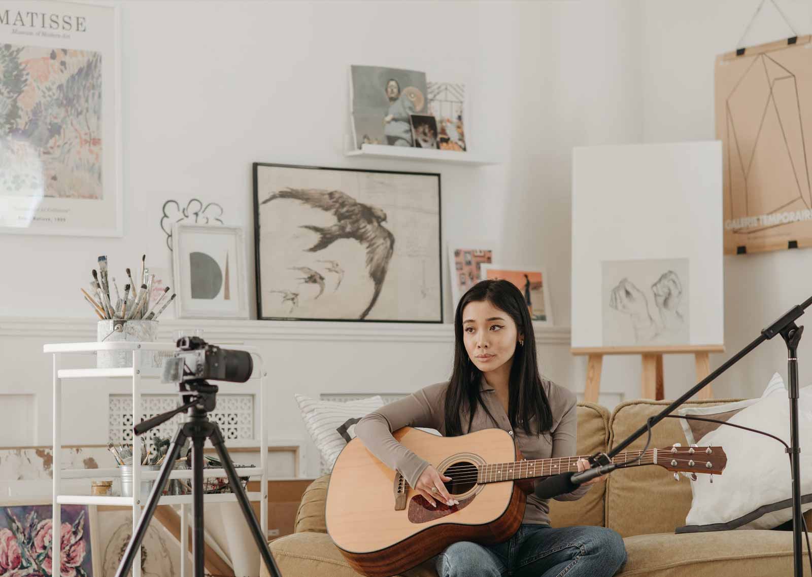 seorang content creator wanita sedang merekam dirinya dengan gitar